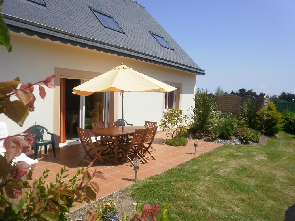 a table and chairs with an umbrella on a patio at Gite bord de mer jacuzzi in Plougrescant
