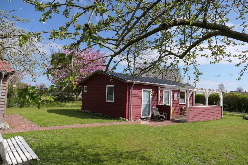 ein rotes Haus mit Veranda auf einem Hof in der Unterkunft Holtdeel in Gelting