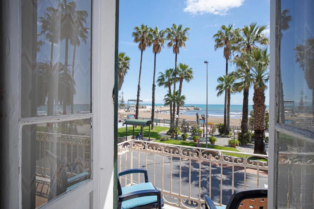 a room with a view of the beach and palm trees at Casa Edda - Sea view in Diano Marina