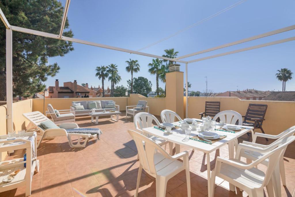a patio with white tables and chairs on a deck at Atico En Islantilla in Huelva