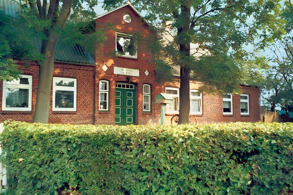 a brick building with a green door and a clock tower at Fewo Hanna Tedsen in Pellworm