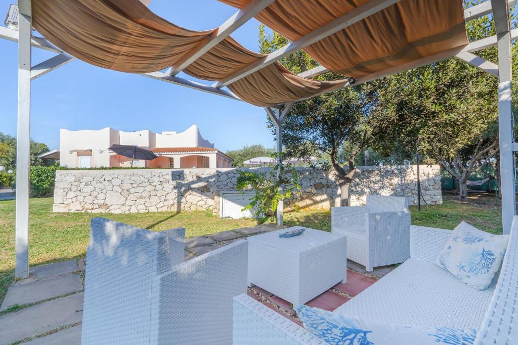 a patio with white furniture and a stone wall at Villa Leale Plemmirio con piscina in Syracuse
