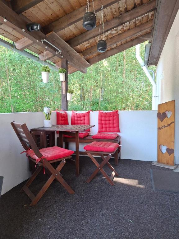 a patio with red cushioned chairs and a wooden table at Im Grünen 2 in Weil der Stadt