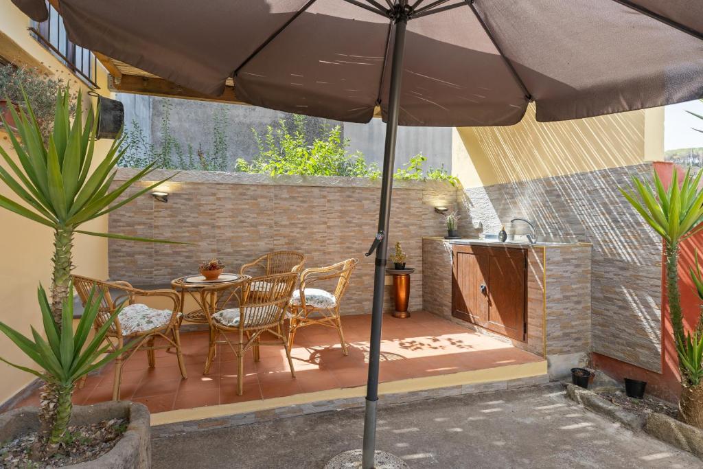 a patio with a table and chairs and an umbrella at Affittacamere Le Muse in Scano Montiferro