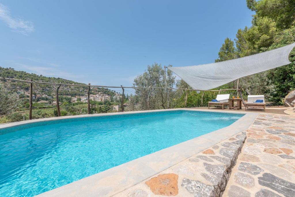 a swimming pool with a hammock and a table and chairs at Villa Cami de la Mar in Port de Soller