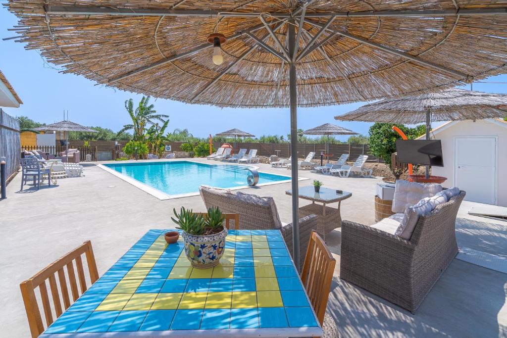 a patio with a table with an umbrella and a pool at Villa Luana con piscina in Noto
