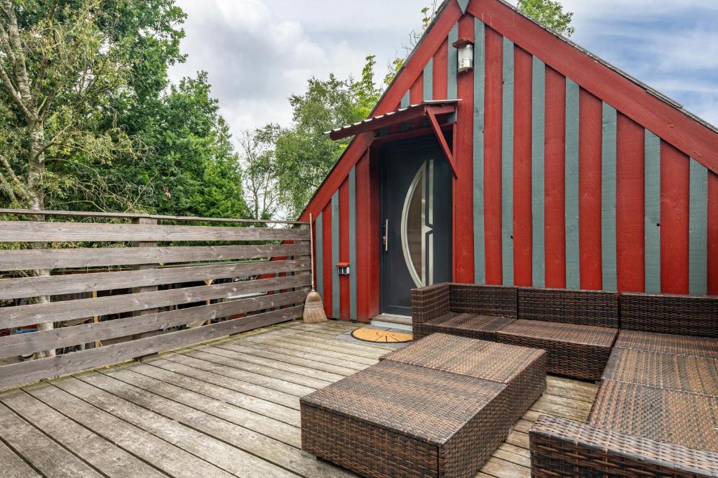 a red building with two benches on a wooden deck at Zum Kanal in Steinau