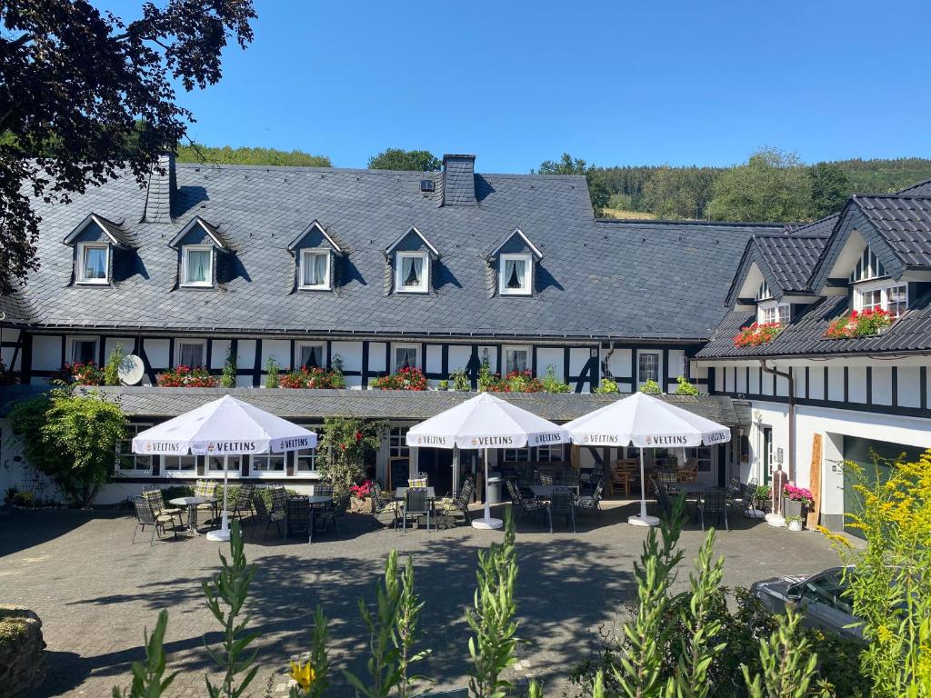 a large building with tables and white umbrellas at Ferienhof Pohl-Optimal für Familien in Lennestadt