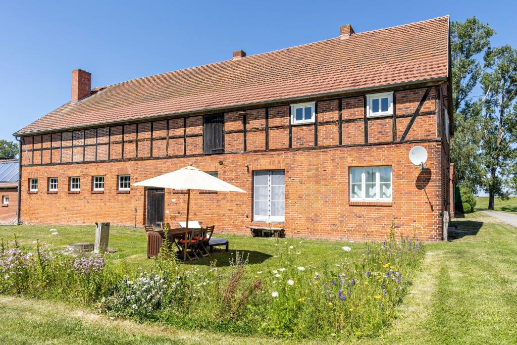 a brick building with an umbrella in front of it at Der Flusshof, Scheunenwohnung in Werben