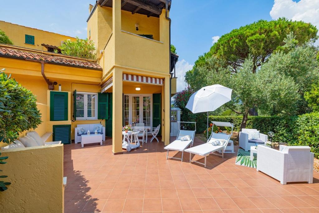 a patio with white chairs and an umbrella at Isabel Beach and Bike in Finale Ligure