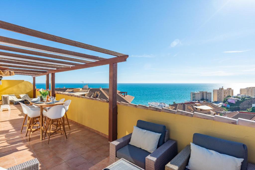 a balcony with chairs and a table and the ocean at Modern penthouse in Fuengirola