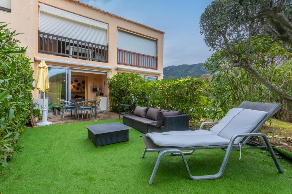 a patio with chairs and a table on a lawn at Studio Saint Clair pieds dans l'eau in Le Lavandou