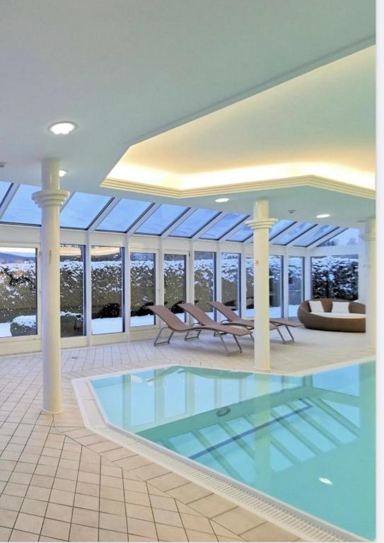 a large pool in a house with chairs and tables at Apartment Blackforest-Schluchsee in Schluchsee