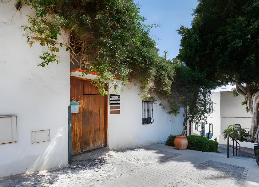 a white building with a wooden door and trees at Casa Rústica San Francisco 1 in Telde