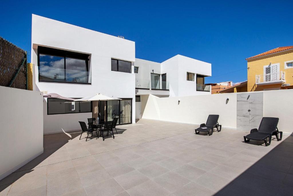 a patio with chairs and an umbrella on a building at Las Cuestitas Sol in Pájara