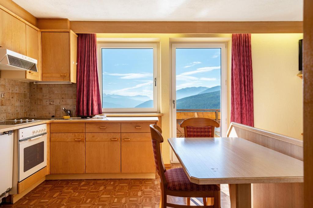 a kitchen with a table and two windows at Apt Waldblick in Maranza