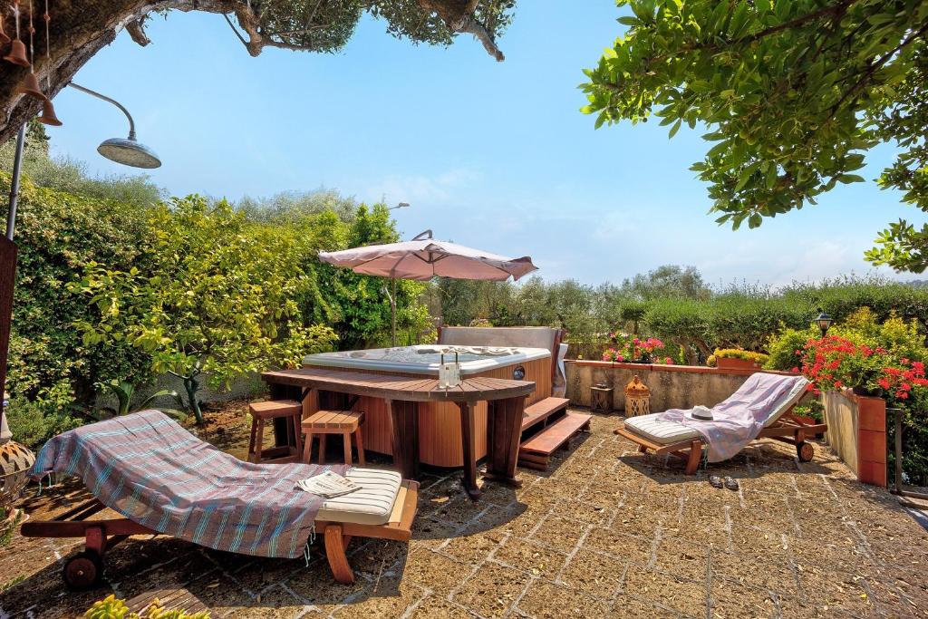 a patio with a table and an umbrella and chairs at Ca dei Tati -Citr 1181 with Jacuzzi in Imperia