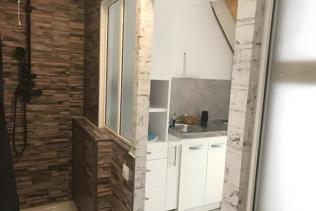 a kitchen with white cabinets and a brick wall at La Maison Defanny - 2 in Muides-sur-Loire