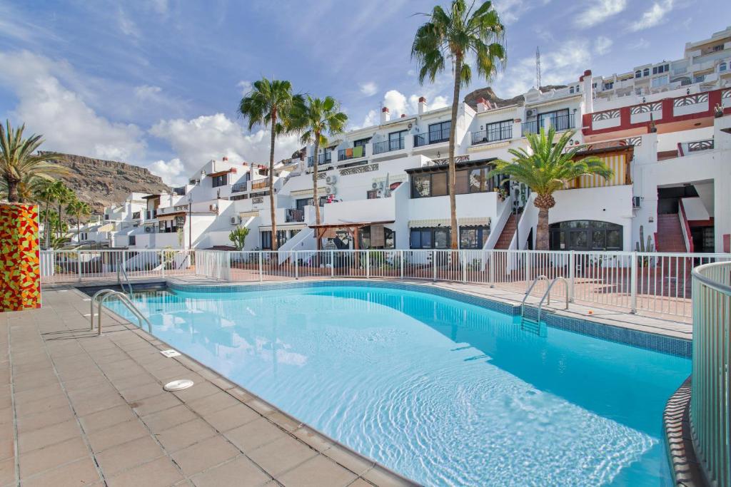 a swimming pool in front of a building with palm trees at Daniel House in Mogán