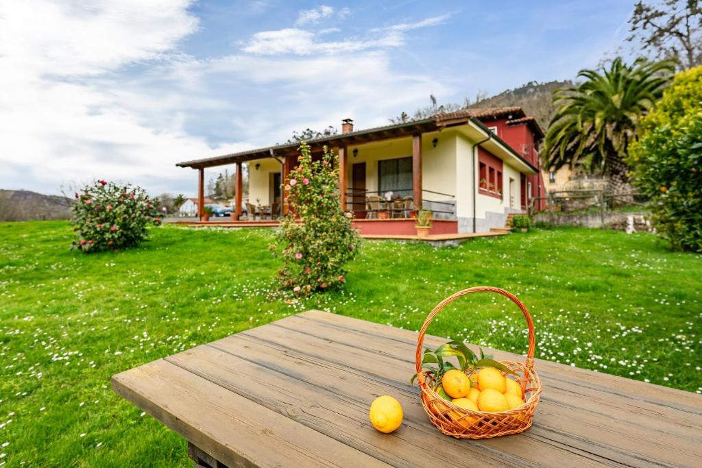 a basket of fruit on a table in front of a house at Apartamentos Les Cuartes in Cangas de Onís