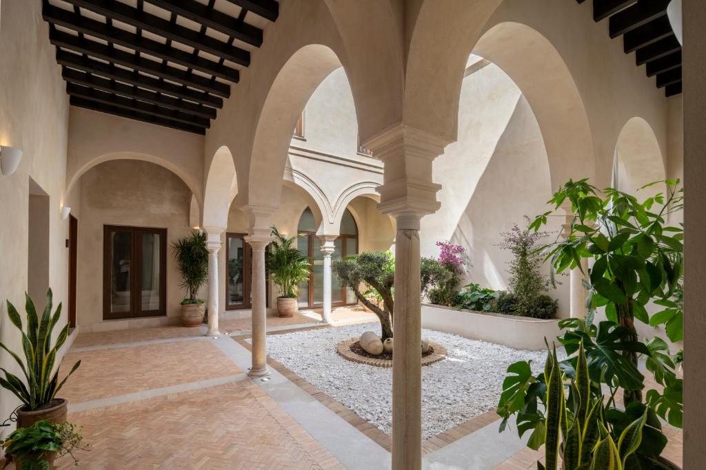 an indoor courtyard with arches and potted plants at Magno Collection Palacio de Becas in Seville