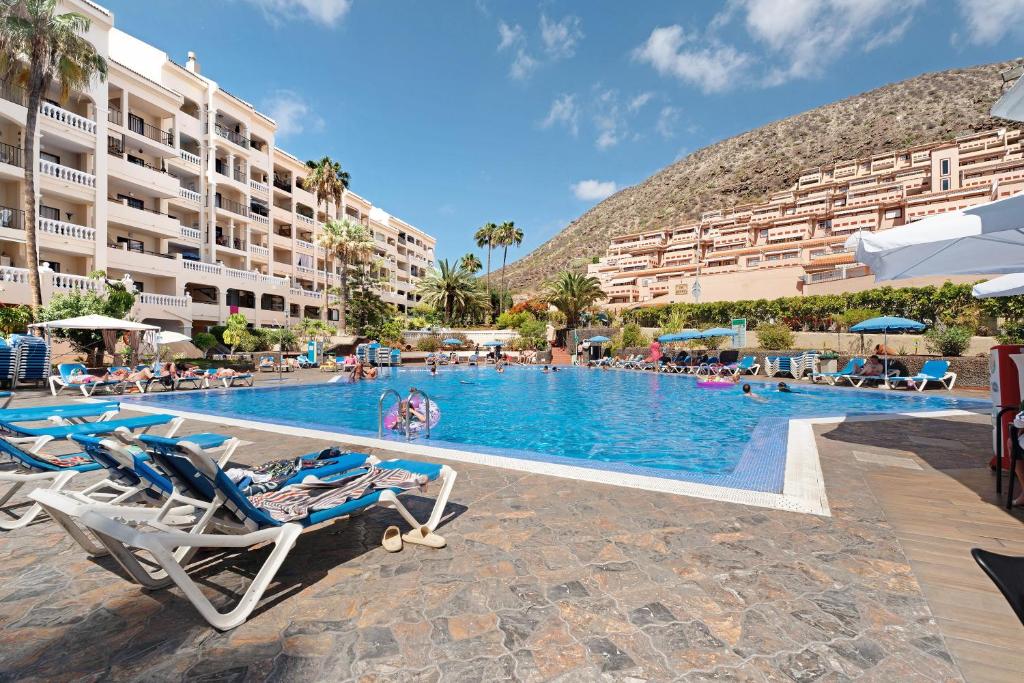 a pool at a resort with chairs and people in it at Castle Harbour in Los Cristianos