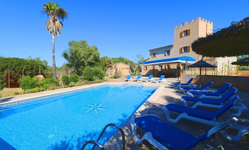 a swimming pool with blue lounge chairs next to a house at Can Palea in Campos