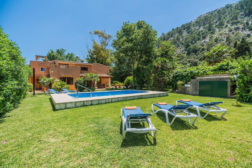 a yard with chairs and a pool and a house at Sontuiri den Jaume in Pollença