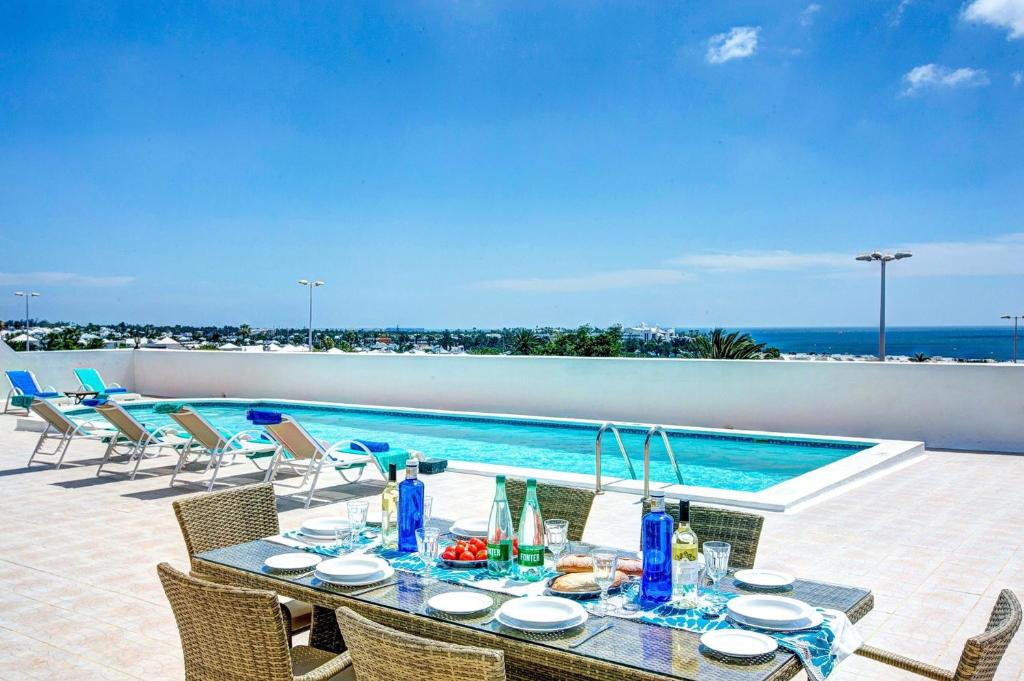 a dining table with chairs and a swimming pool at Casa Paula in Yaiza