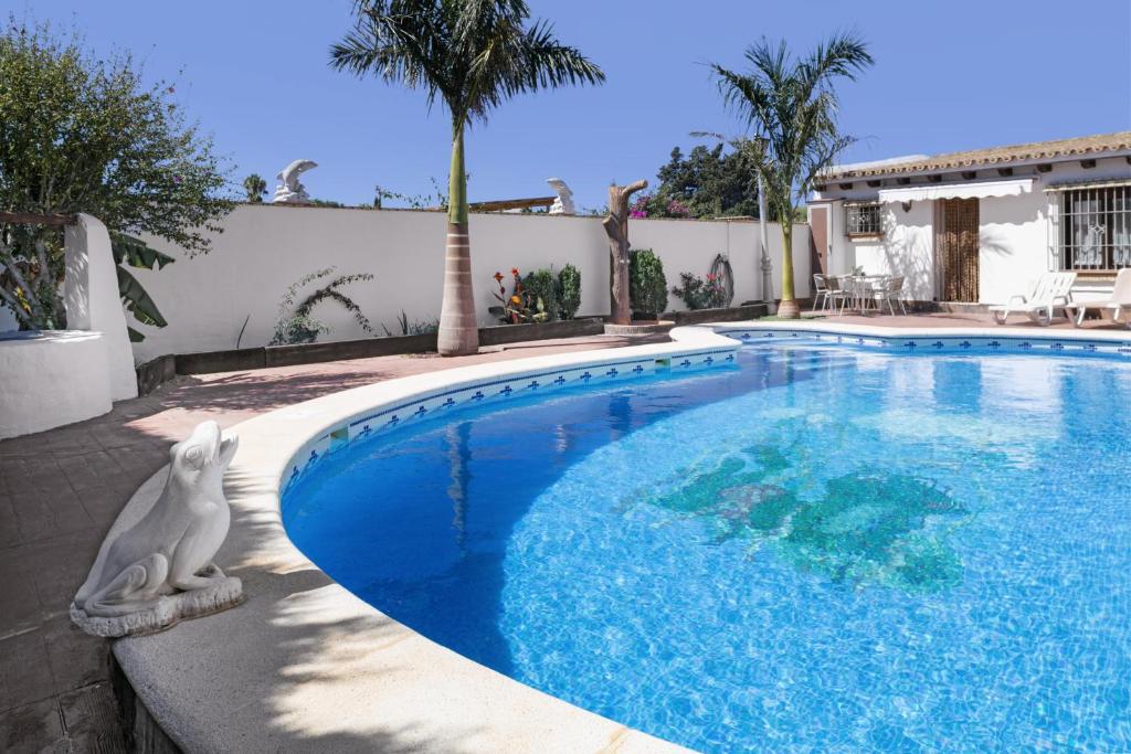 a swimming pool with a statue next to a house at Cortijo Entrepinares in Conil de la Frontera