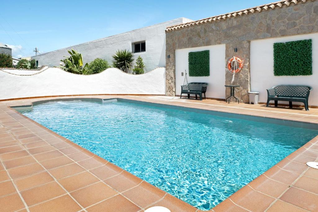a swimming pool with blue water in a yard at Chalet Fuente2 piscina común famila in Conil de la Frontera