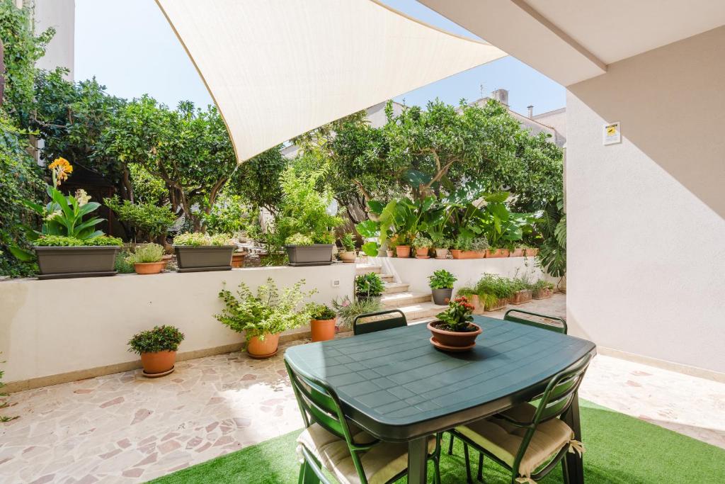 a patio with a table and chairs and potted plants at Ardesia Vacanze in Valderice