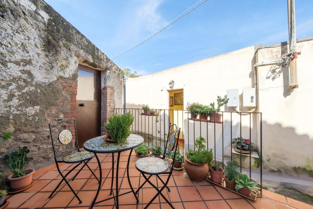a patio with two tables and potted plants at Holiday Home Tommaso e Martina in Savoca