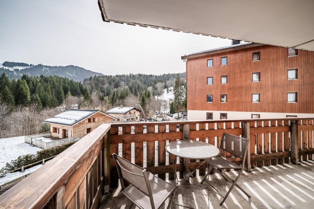 a balcony with a table and chairs and a building at Appart 6 pers – Accès direct Ski in Morillon