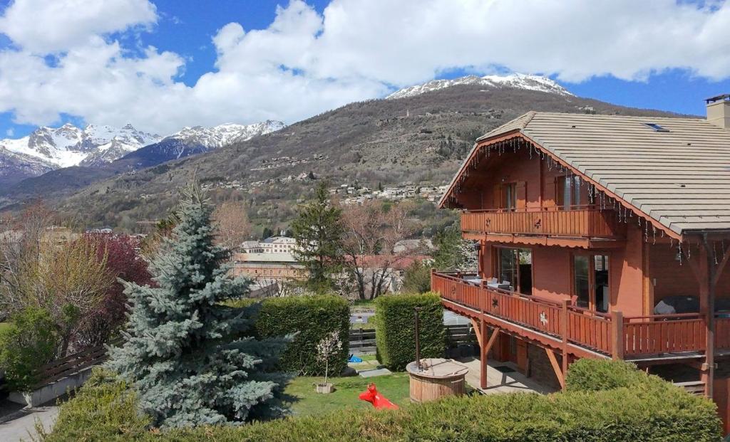 a wooden house with mountains in the background at Chambre D'hôte au Chalet Datcha in Briançon