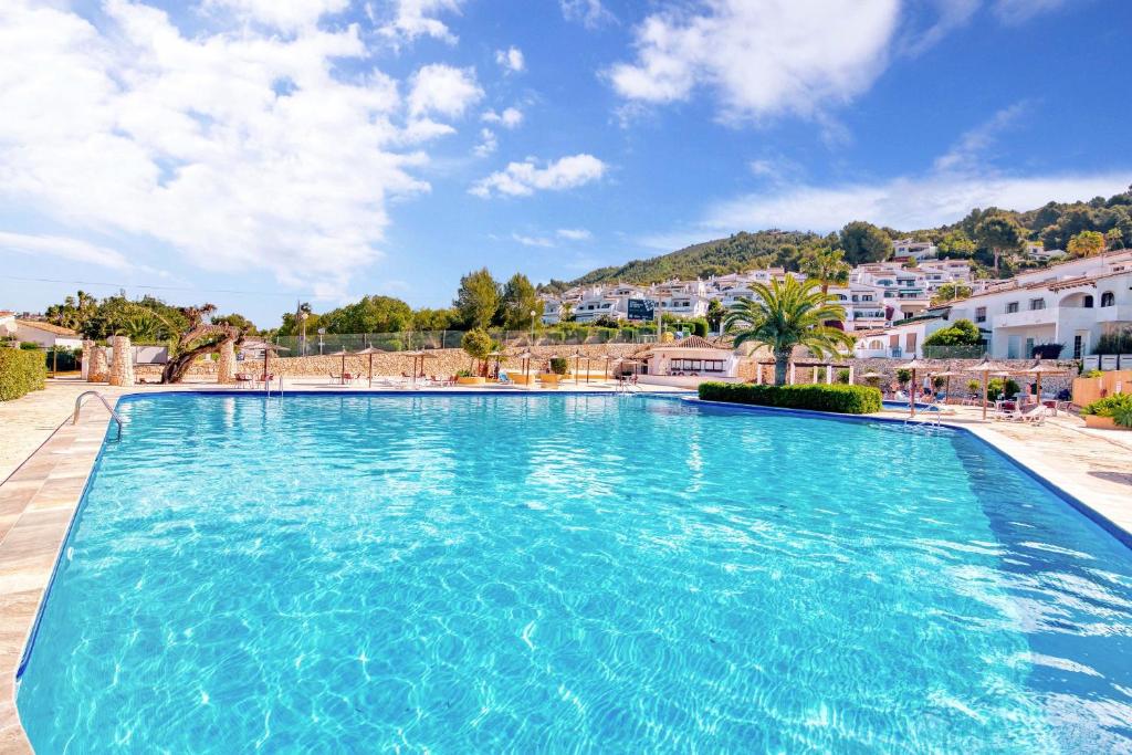a large blue swimming pool with buildings in the background at Amor Supremo in Cumbre del Sol