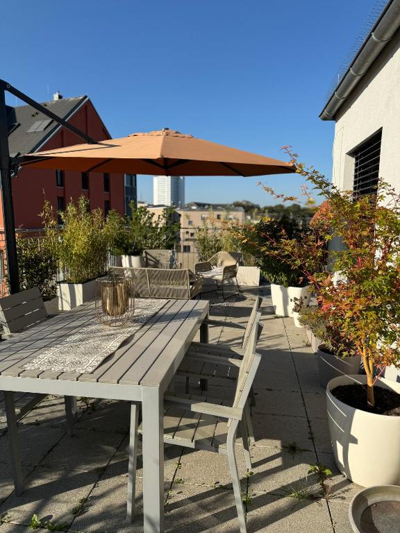 a wooden table with chairs and an umbrella on a patio at 180qm Penthouse mit Sonnenterrasse in Rostock