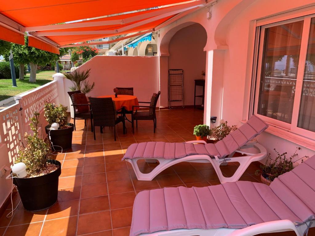 a patio with pink benches and a table on a balcony at Beach Bungalow in Torrox