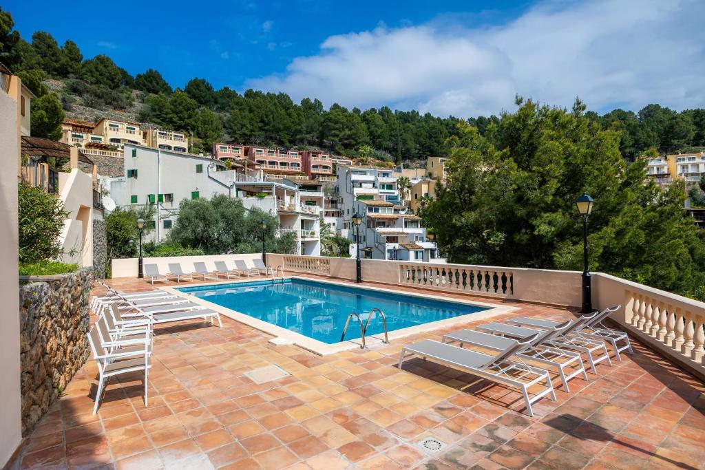 a swimming pool with lounge chairs and a building at Villa Carla in Port de Soller