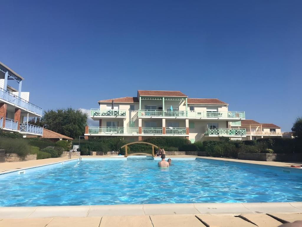 a man in a swimming pool in front of a building at M112 - L'orée Du Golf in Pornic