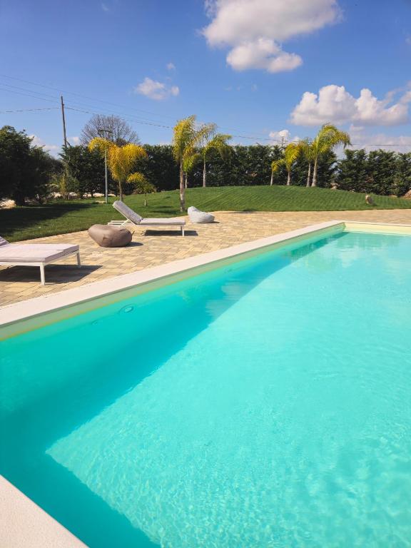 a large blue swimming pool with two chairs and a table at Villa Nilde in Triggianello