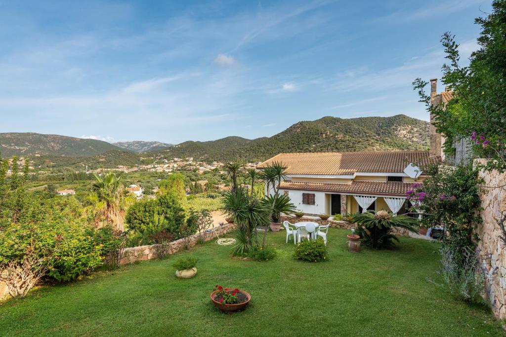 a garden with a table and chairs and a house at Appartamento Chia Grande in Chia