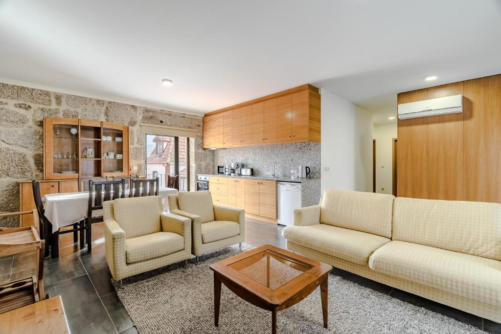 a living room with two couches and a kitchen at Casa Feixa Gerês in Geres