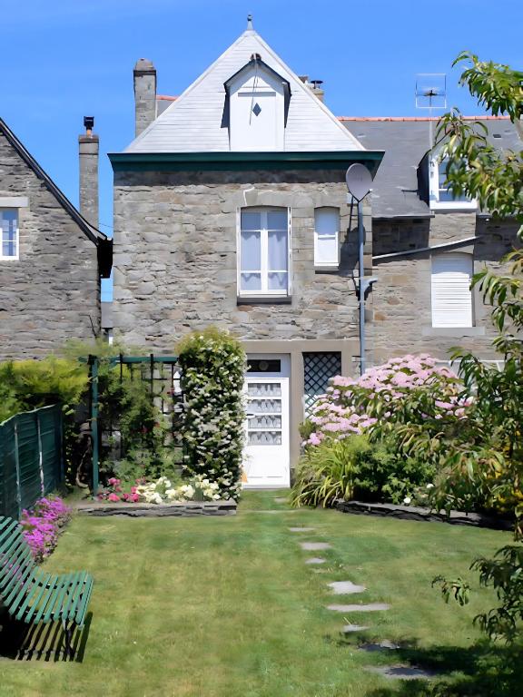 a house with a white door and a yard at Les Flots Bleus Cancale in Cancale