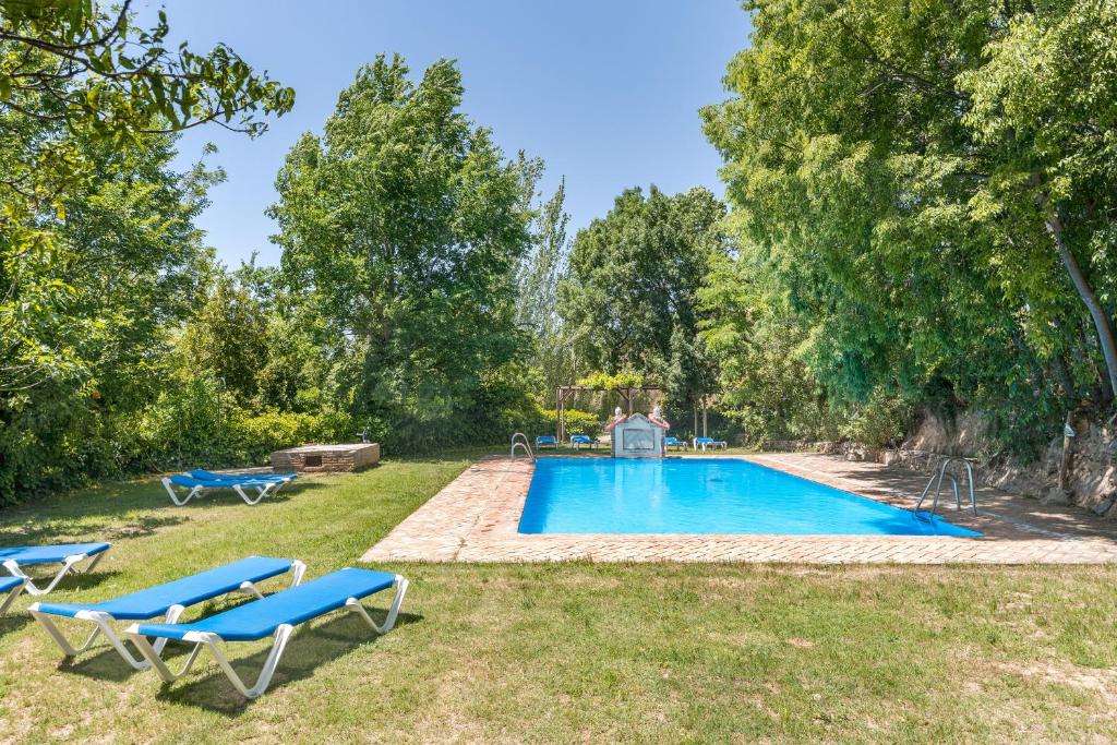 a swimming pool in a yard with two blue lounge chairs at El Cobertizo in La Zubia