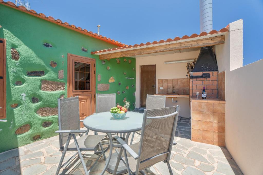 a patio with a table and chairs and a green wall at vv - La Casa Verde in Las Casas