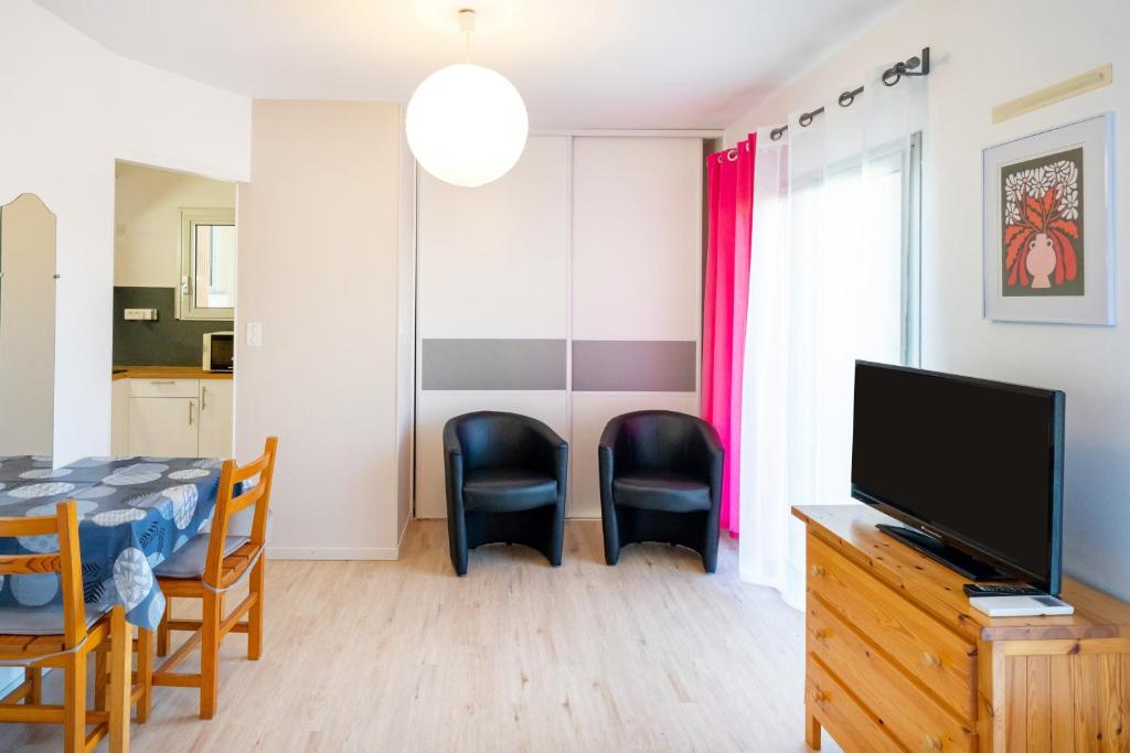 a living room with a tv and a table and chairs at Les Mimosas - Appartement 06 in Cazaubon