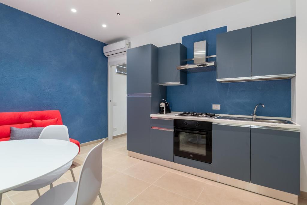 a blue kitchen with a red couch and a table at Verdemare a due passi dal mare in Villaggio Azzurro