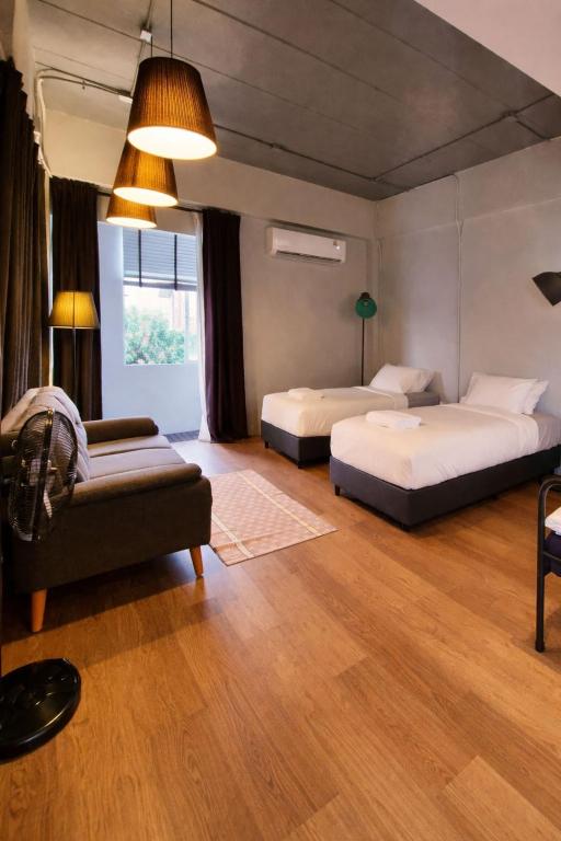 a bedroom with two beds and a couch in a room at Human Touch Room - Soulful Bangkok Hideout in Lat Krabang
