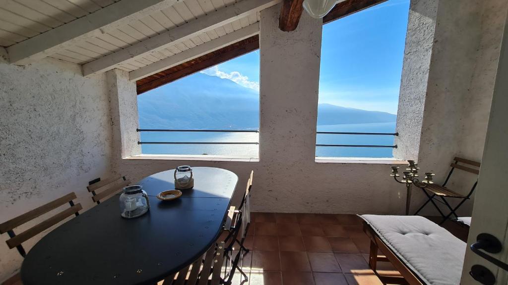 a table and chairs in a room with a large window at Casa borgo Arias Lake View in Tremosine Sul Garda